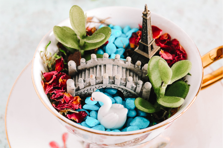 mini garden in a white teacup with a bridge, swan and Eiffel Tower